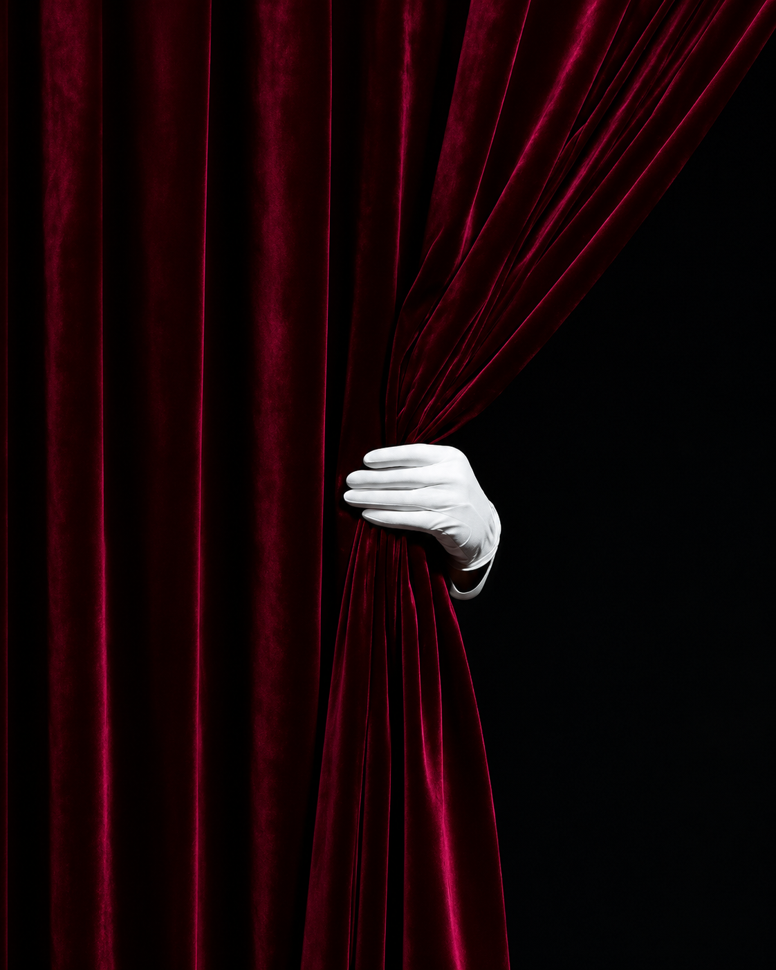 Burgundy theater curtain with white-gloved hand